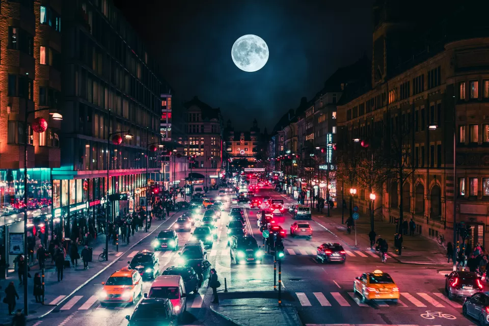 View of busy street at night with full moon in background in Stockholm, Sweden